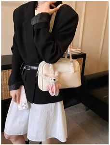 Detail of off-white lychee pattern leather handbag with cute rabbit plush charm