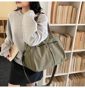 Dettaglio della borsa da viaggio in tela verde oliva con cuciture rosse e zip metalliche
