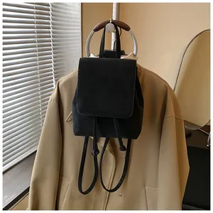 Detail of matte black mini backpack with flap drawstring closure on trench coat