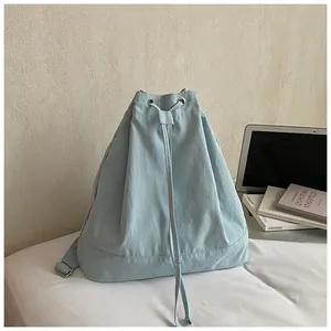 Detail view of light blue drawstring backpack with metal rings on a white surface