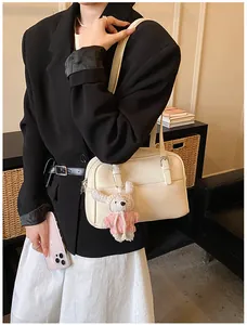 Litchi pattern cream white crossbody bag with cute rabbit pendant on a model