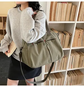 Dettaglio borsa da viaggio in tela oliva con tasche a zip e cuciture rosse a vista