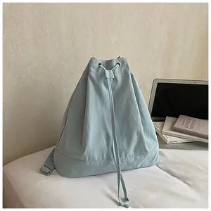 Detail of light blue drawstring backpack with metal eyelets and adjustable strap on desk
