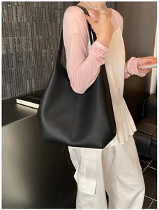 Detail view of large black lychee textured leather tote bag with slim shoulder straps