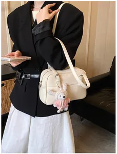 Detail of lychee textured cream shoulder bag with a cute plush bunny charm