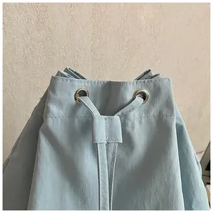 Macro detail of silver metal eyelets and drawstring on a light blue nylon sports bag