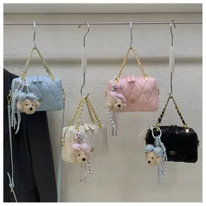 Dettaglio di borse a tracolla trapuntate in blu, beige, rosa e nero con ciondolo a orsetto