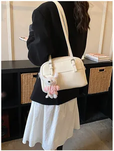 Detail of off-white lychee texture leather shoulder bag with a cute rabbit plush pendant