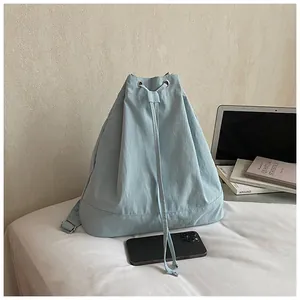 Detail of light blue drawstring backpack with silver eyelets in a minimalist home setting