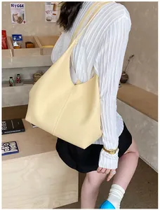 Close-up of a cream-colored leather hobo tote bag worn as a shoulder bag for work