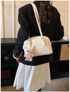 Close-up of white lychee textured handbag with cute teddy bear charm on model side