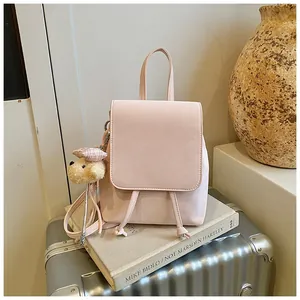 Pink PU leather mini backpack with a cute teddy bear charm in a travel setting