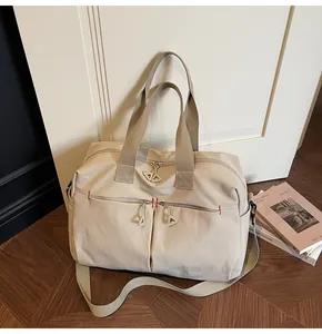 Dettaglio borsa da viaggio in tela con cuciture rosse e tirante zip a triangolo