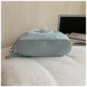 Detail of the flat oval base and reinforced stitching on a light blue nylon bag