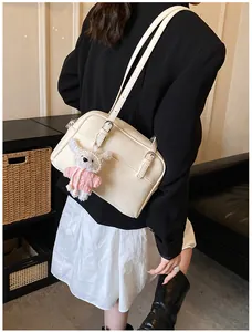 Detail of off-white lychee texture shoulder bag with cute plush pendant and metal buckle