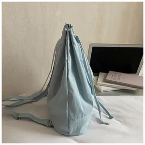 Detail of light blue drawstring backpack showing nylon fabric texture and adjustable strap
