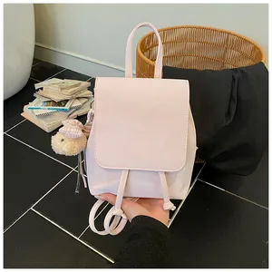 Detail view of light pink faux leather backpack with plush bear charm and drawstring