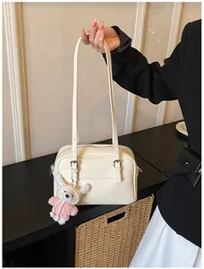 Detail of cream lychee texture crossbody bag with adjustable silver buckle and plush charm