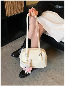 Close-up of beige lychee leather tote bag featuring a cute knitted rabbit pendant charm