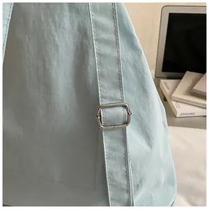 Detail of mint blue ripstop fabric texture and adjustable silver metal buckle on bag strap