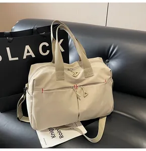 Dettaglio borsa da viaggio beige con doppie tasche a cerniera e cuciture rosse rinforzate