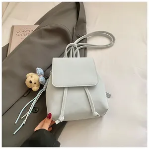 Detail of light blue mini backpack with drawstring closure and plush bear charm