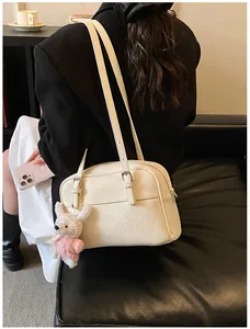 Detail of cream lychee texture crossbody bag with cute pink rabbit plush pendant