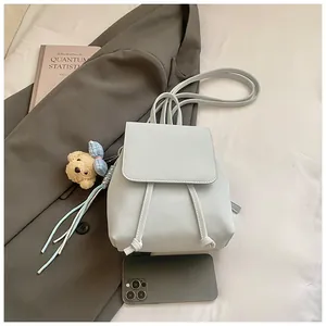 Close-up of light blue PU leather backpack with drawstring closure and cute bear pendant