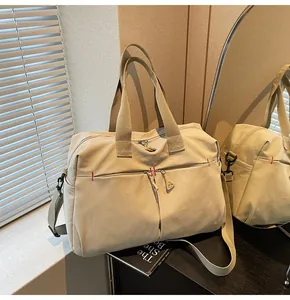 Dettaglio borsa da viaggio in tela con cuciture rosse e doppie tasche con zip