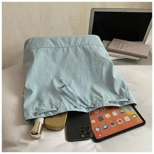 Detail of mint blue drawstring tote showing spacious interior with tablet and cosmetics