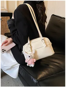 Close-up of litchi texture on beige shoulder bag with cute plush pendant detail