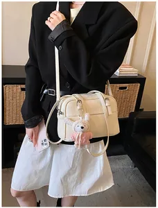 Detail of off-white lychee pattern crossbody bag with a cute plush rabbit charm