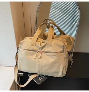 Dettaglio della borsa da viaggio in tela kaki con cuciture rosse sulle tasche anteriori con zip