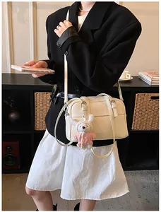 Close-up of creamy white lychee-patterned crossbody bag with cute plush rabbit charm