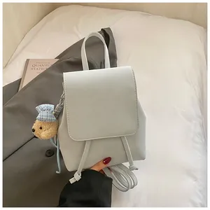 Detail of light blue-gray mini backpack with plush bear charm and drawstring closure