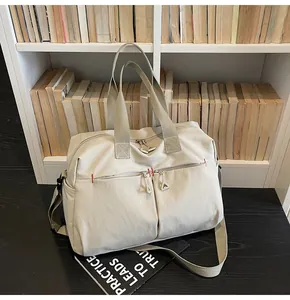 Dettaglio della borsa da viaggio in tela beige con tasche a zip e manici rinforzati