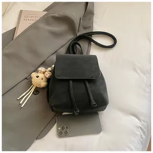 Detail of black matte leather mini backpack with drawstring and teddy bear charm accessory