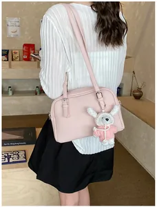 Detail of pink lychee textured crossbody bag featuring a cute bunny plush charm accessory