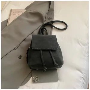 Mini black matte leather backpack with drawstring closure shown next to a smartphone