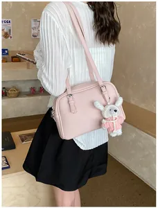 Close-up of pink litchi pattern leather bag with silver buckle and plush bunny charm