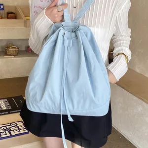 Detail of light blue canvas drawstring backpack showing fabric texture in casual indoor setting