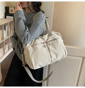 Dettaglio della borsa da viaggio in tela beige con cerniere e manici intrecciati