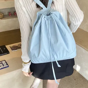 Detail of light blue canvas drawstring backpack showing metallic eyelets and slim straps