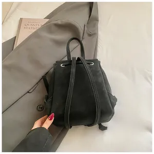 Detail view of the sleek black mini backpack with drawstring closure on a light background