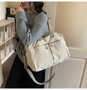 Grande borsa da viaggio in tela beige con multitasche indossata da un modello in interno