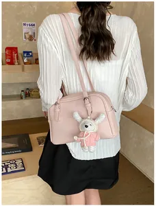 Pink lychee pattern leather shoulder bag styled with cute plush charm on a model