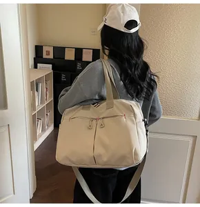 Modello con borsa da viaggio grande in tela beige e tracolla regolabile in spalla