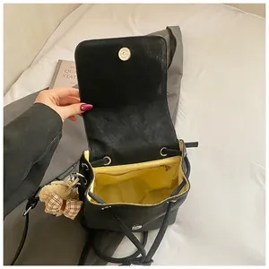 Top view of black leather backpack showing yellow lining and plush bear keychain