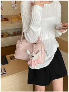 Detail view of pink lychee leather crossbody bag with cute plush animal charm accessory