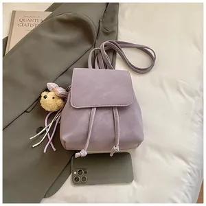 Detail of purple PU leather mini backpack with flap closure and plush bear charm